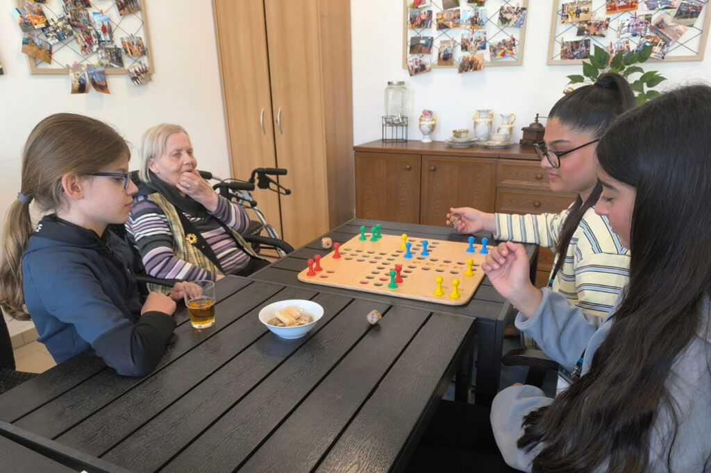 Jugendliche spielen mit einer Bewohnerin Brettspiele